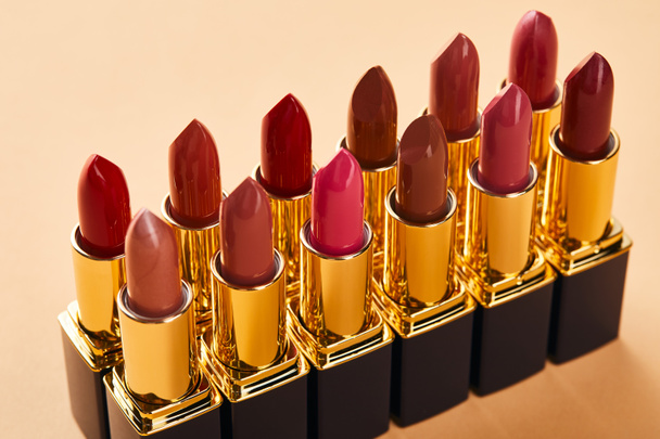 Close up of red shades of lipstick in tubes on beige  - Фото, зображення