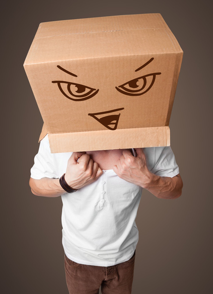 Young man gesturing with a cardboard box on his head with evil f - Valokuva, kuva