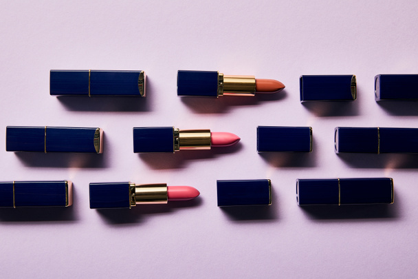 flat lay with different pink shades of lipsticks in tubes on violet    - Foto, Bild