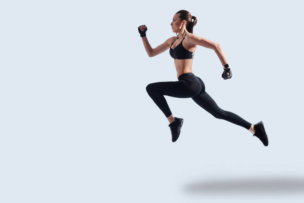 Achieving best results. Full length of attractive young woman in sports clothing exercising while hovering against grey background - Foto, Imagem