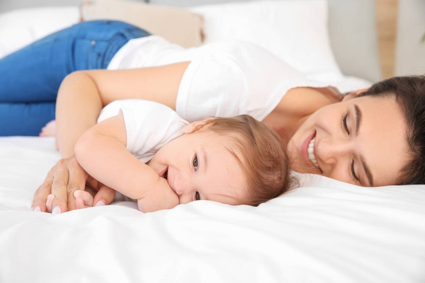 ベッドに横たわっているかわいい赤ちゃんと幸せな母親 - 写真・画像