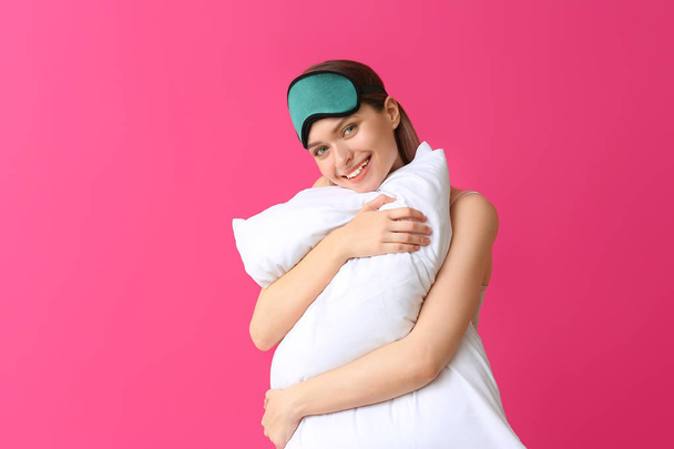 Young woman with pillow and sleep mask on color background - Фото, изображение