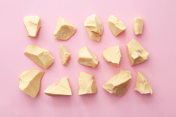 Pieces of cocoa butter on color background - Φωτογραφία, εικόνα