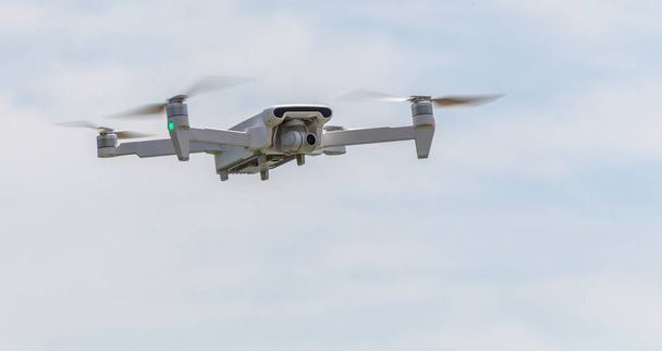 Un drone filmant professionnel vole dans les airs à basse altitude contre un ciel bleu. Drone fait des photos. Nouvelle technologie moderne. Arrière-plan prêt avec place pour votre texte
 - Photo, image