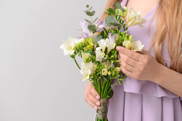 Woman with beautiful freesia flowers on light background - Foto, imagen