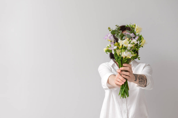 Woman with beautiful freesia flowers on light background - Фото, изображение