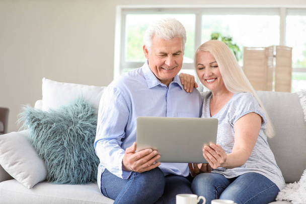 Portrait de couple mature heureux avec ordinateur portable à la maison
 - Photo, image