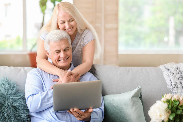 Portrait de couple mature heureux avec ordinateur portable à la maison
 - Photo, image