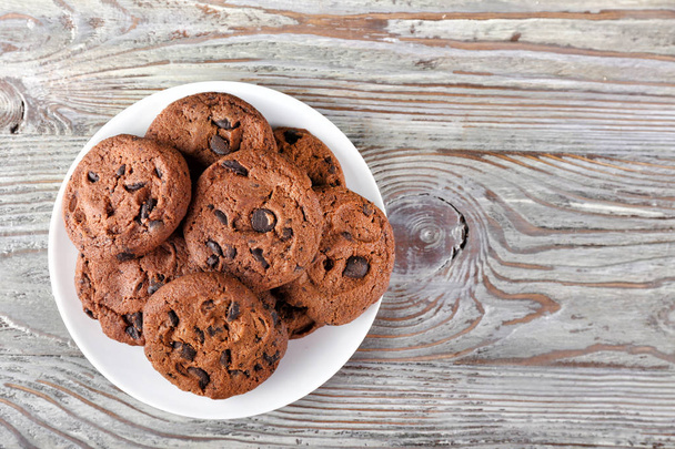 Πλάκα με νόστιμα μπισκότα σοκολάτας στο ξύλινο τραπέζι - Φωτογραφία, εικόνα