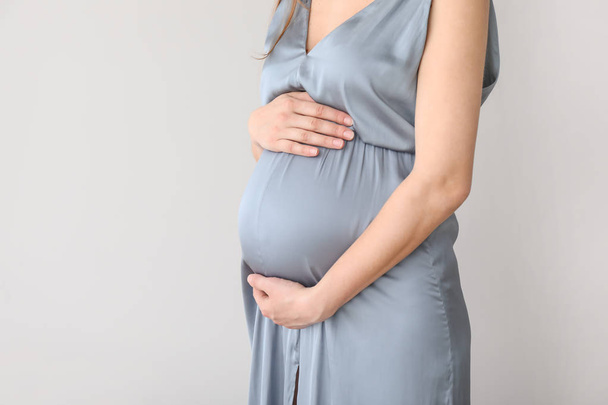 Młoda kobieta w ciąży na jasnym tle - Zdjęcie, obraz