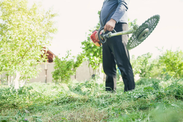 Arbeiter mäht Gras mit einem Rasentrimmer. - Foto, Bild