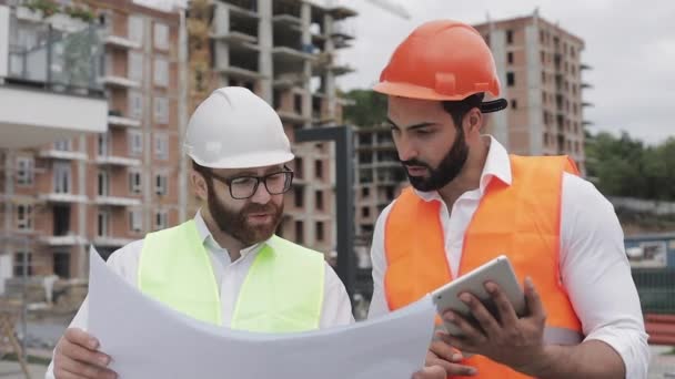 Building a residential complex or business center. Team of engineers men with a tablet and drawing analyzing plans construction builders job activity. - Filmagem, Vídeo