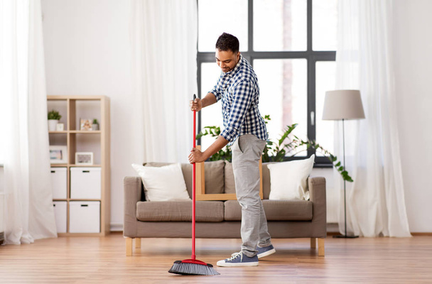 man with broom cleaning floor at home - Fotoğraf, Görsel