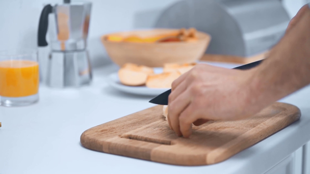 περικομμένη όψη του ανθρώπου ξεφλούδισμα μπανάνα και κοπή σε ξύλινο σανίδα κοπής στην κουζίνα - Πλάνα, βίντεο