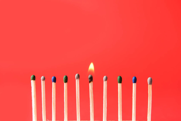 One burning match among non-burning ones on color background. Concept of uniqueness - Photo, Image