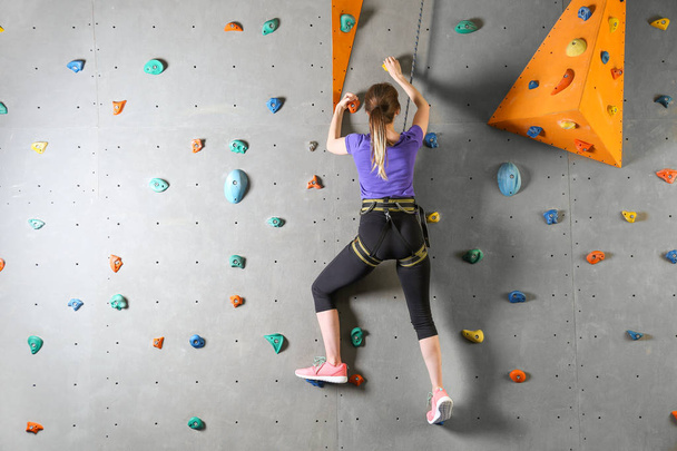 Young woman climbing wall in gym - Photo, Image