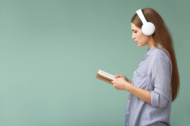 Mujer joven escuchando música y leyendo libro sobre fondo de color
 - Foto, Imagen