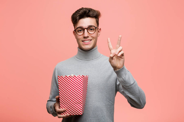Young intellectual man holding a popcorn bucket having some great idea, concept of creativity. - Photo, Image