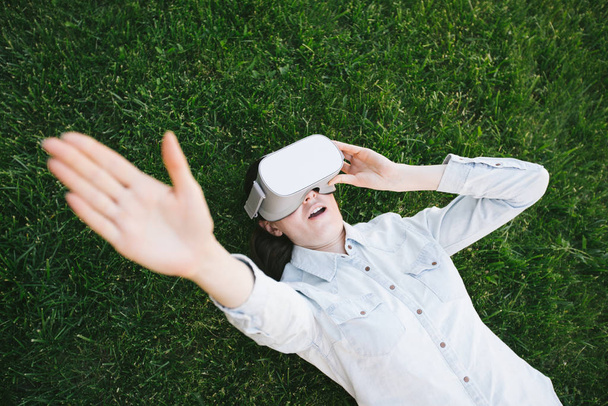 Žena používající virtuální reality brýle venku na zelené trávě - Fotografie, Obrázek