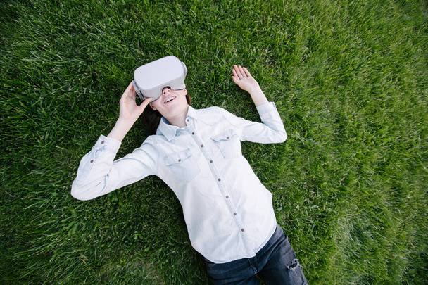 Kobieta za pomocą okularów wirtualnej rzeczywistości na zewnątrz na zielonej trawie - Zdjęcie, obraz