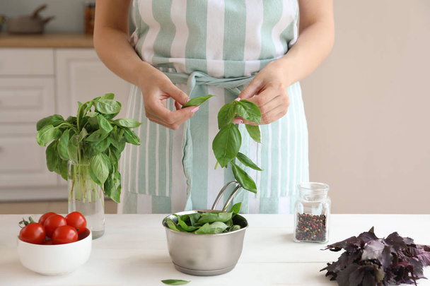 Woman with fresh basil in kitchen - Photo, image