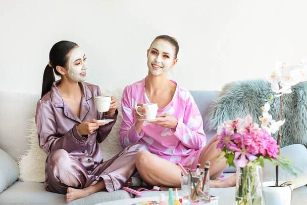 Красивые молодые женщины в масках для лица пьют чай дома
 - Фото, изображение