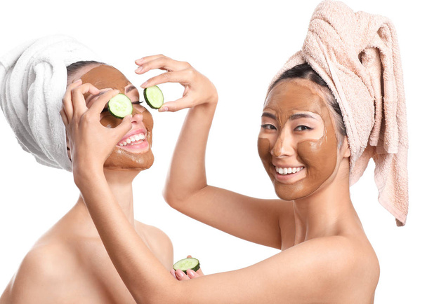 schöne Frauen mit Gesichtsmasken und Gurkenscheiben auf weißem Hintergrund - Foto, Bild