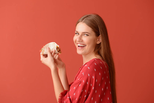 Woman eating tasty taco on color background - Photo, Image