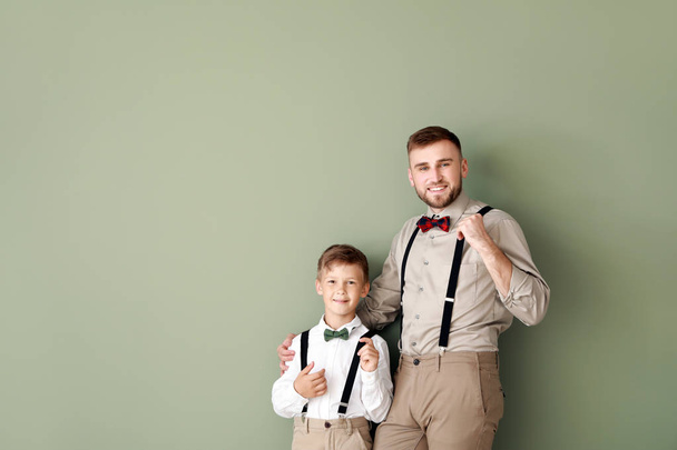 Portrait of fashionable father and son on color background - Foto, imagen