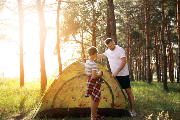 父と彼の幼い息子は、森の中にキャンプテントを置く - 写真・画像