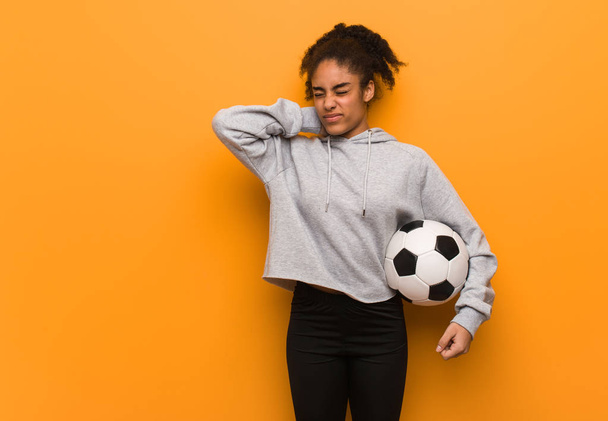 Молодая черная женщина, страдающая от боли в шее. Холдинг футбольный мяч
. - Фото, изображение