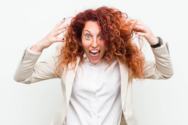 Young natural redhead business woman isolated against white background celebrating a victory or success, he is surprised and shocked. - Photo, Image