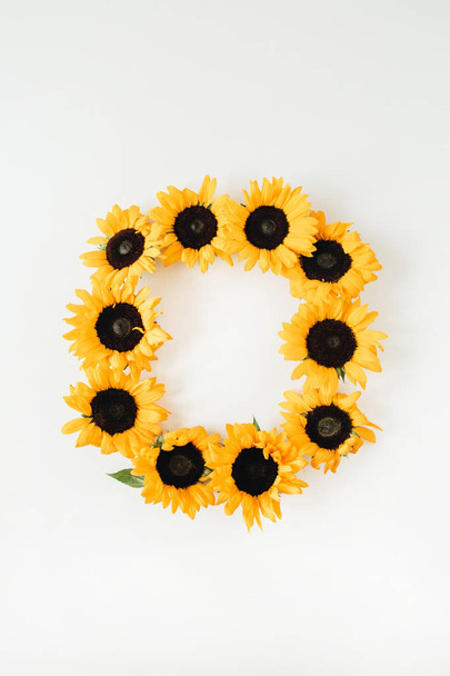 Krans frame gemaakt van zonnebloemen met kopieerruimte op witte achtergrond. Platte lay, bovenaanzicht zomerbloemen mock up template. - Foto, afbeelding