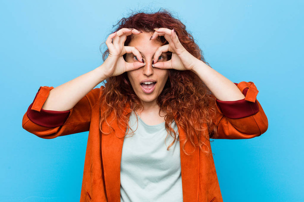 Young redhead elegant woman showing okay sign over eyes - Foto, imagen