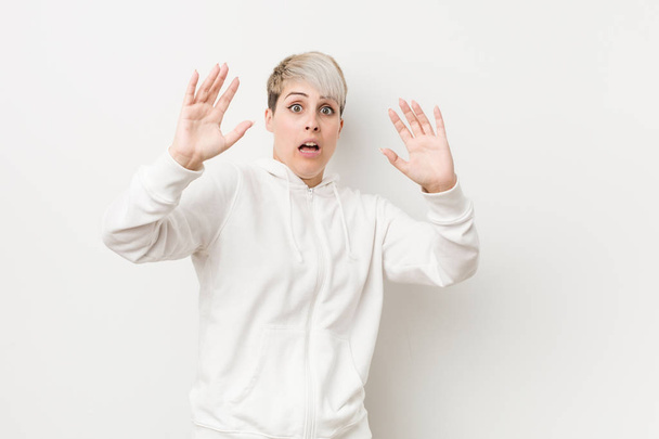 Young curvy woman wearing a white hoodie being shocked due to an imminent danger - Photo, Image