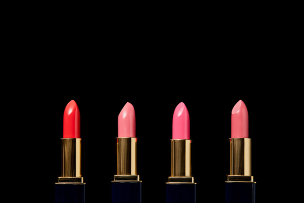 various shades of lipsticks in tubes isolated on black    - Photo, Image