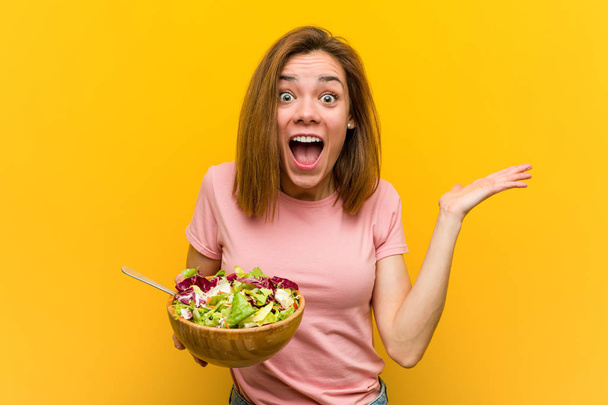 Young healthy woman holding a salad celebrating a victory or success - Photo, Image