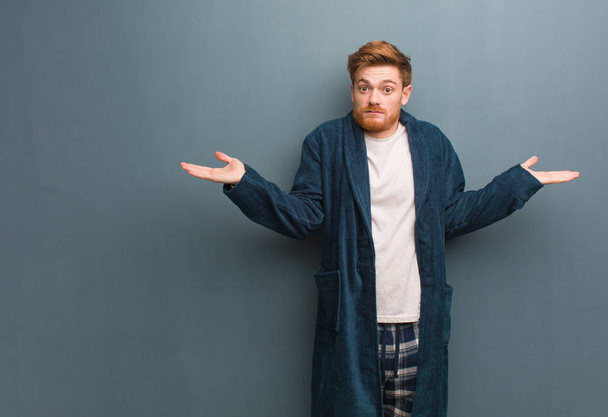 Young redhead man in pajama confused and doubtful - Photo, Image