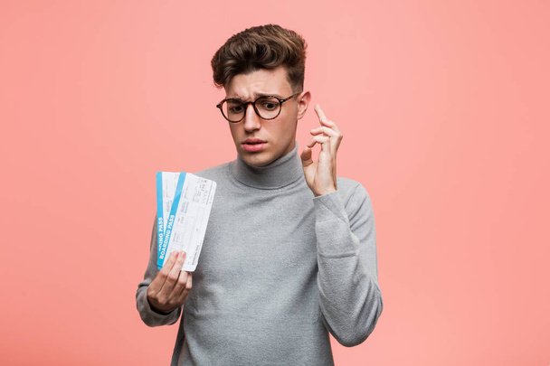 Giovane uomo fresco in possesso di un biglietto aereo incrociando le dita per avere fortuna
 - Foto, immagini