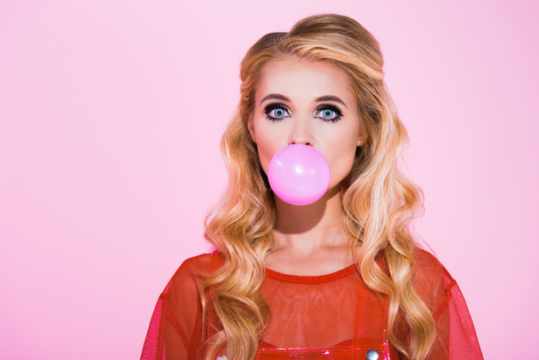 beautiful girl blowing bubble gum isolated on pink, doll concept - 写真・画像