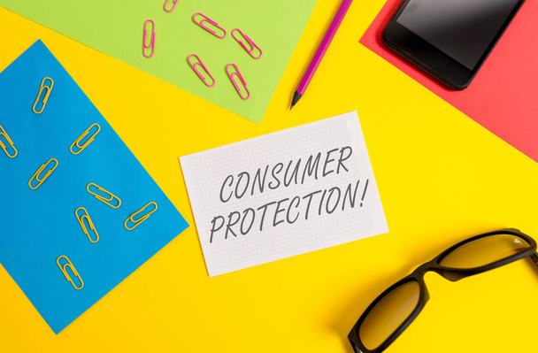 消費者保護を示すテキスト記号です。消費者の権利の保護を確保するための概念的な写真の公正取引の法律ペーパーシートペンシルクリップスマートフォンメガネノートブックカラー背景. - 写真・画像