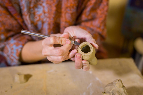 Woman potter making ceramic souvenir penny whistle in pottery workshop - 写真・画像