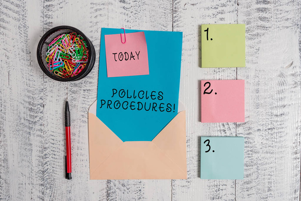 Writing note showing Policies Procedures. Business photo showcasing Influence Major Decisions and Actions Rules Guidelines Envelope letter sticky note ballpoint clips on wooden background. - Photo, Image