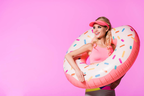 hermosa chica feliz con anillo de natación de donut inflable aislado en rosa, concepto de muñeca
 - Foto, imagen