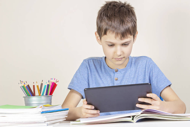 Kid with tablet computer sitting at table with books notebooks - Photo, Image