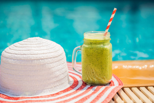 Зелені коктейлі зі шпинату та банана на фоні басейну. Здорова їжа, здорові коктейлі
 - Фото, зображення