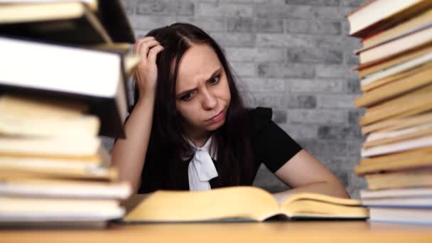 Woman student boring reading book at library with a lot of books in university. Student disheartened reading book for examination. - Video