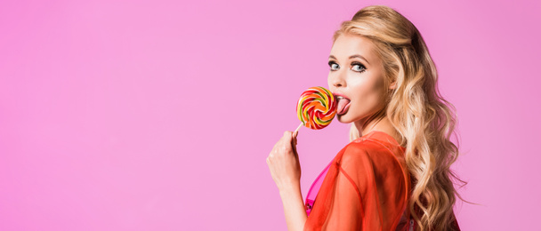 panoramic shot of beautiful girl licking lollipop isolated on pink, doll concept - Фото, зображення