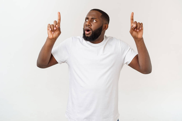 Young amazed African American pointing his finger at white background with copy space for your advertisement - Foto, afbeelding