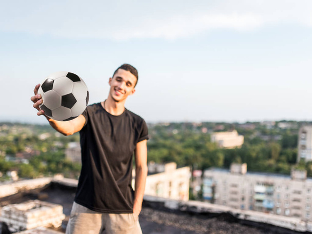 Mies leikkii pallolla ulkona katolla kaupungin taustalla
 - Valokuva, kuva